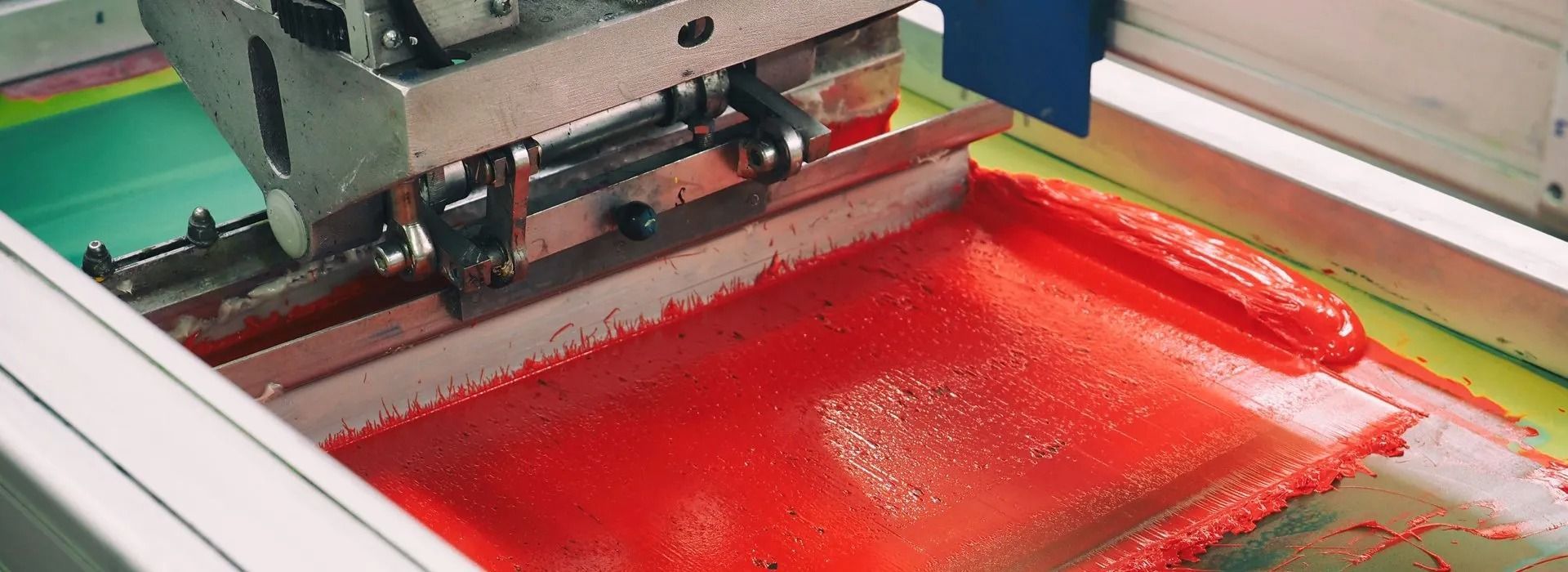 Screen printing machine applying red ink.