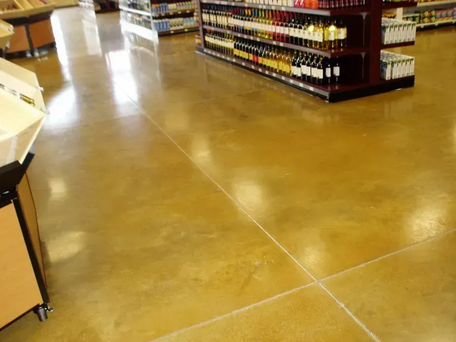 Polished, golden-toned concrete floor in a grocery store, with shelves stocked with products.