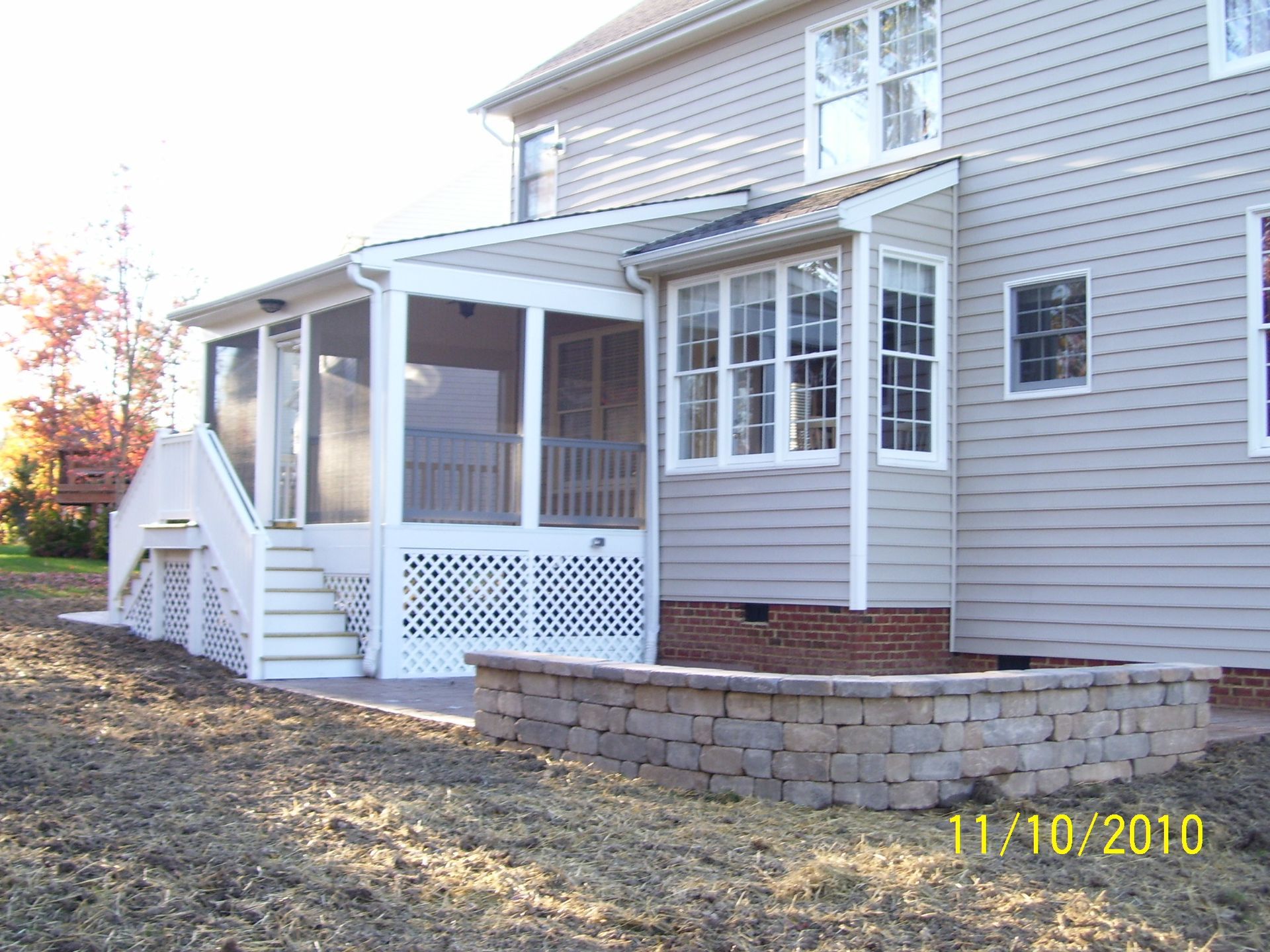 Screened porch and bay window on a house with stone retaining wall.