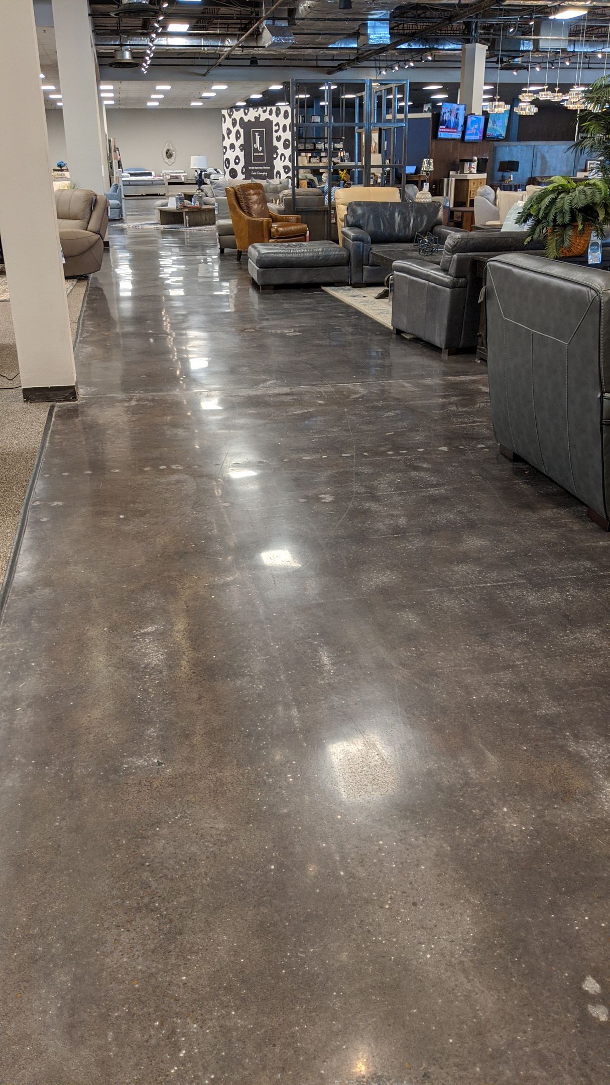 Polished concrete floor in a furniture store, with various sofas and displays in the background.