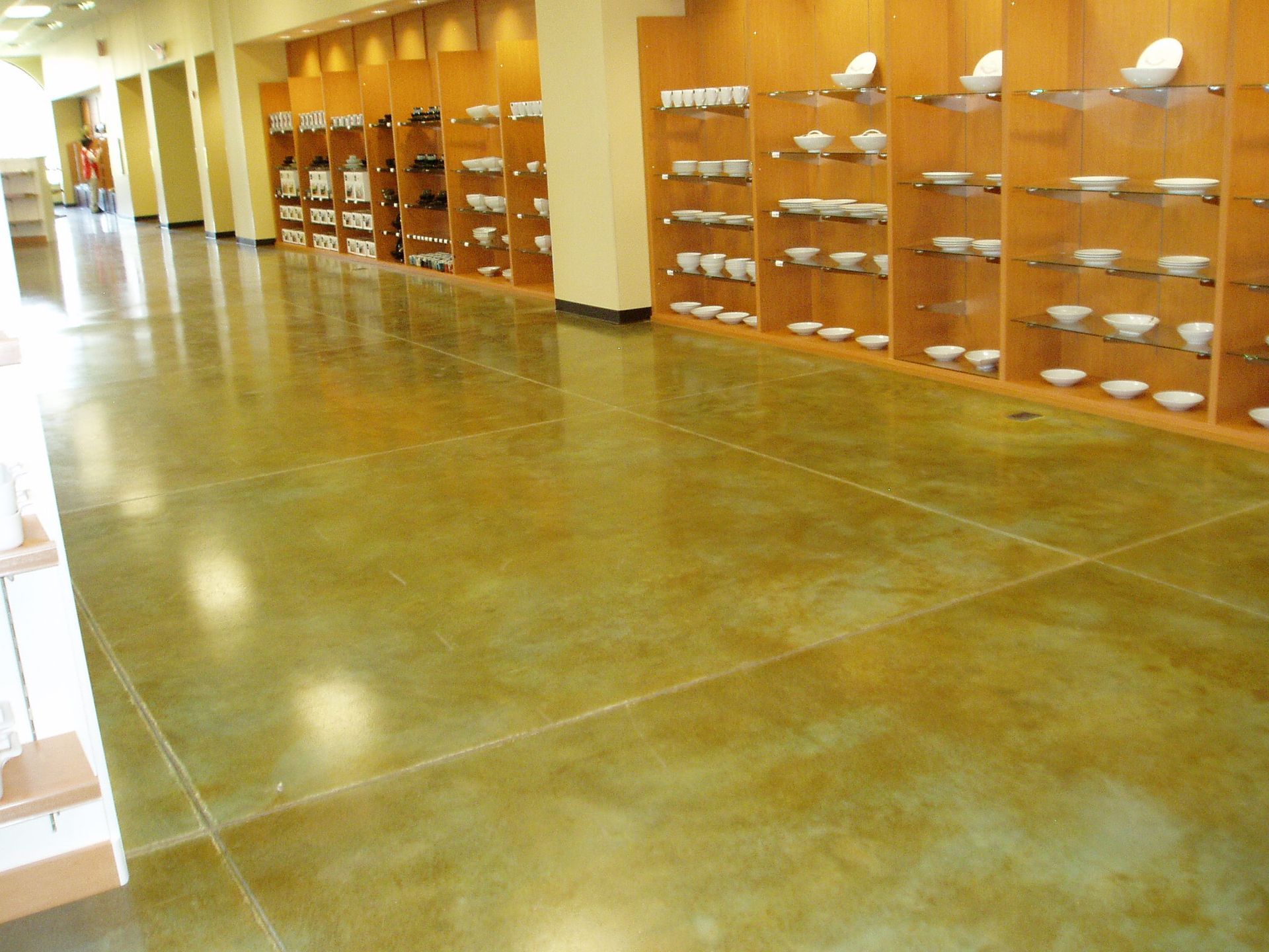 Polished concrete floor in a store with shelves of white dishware along the walls.