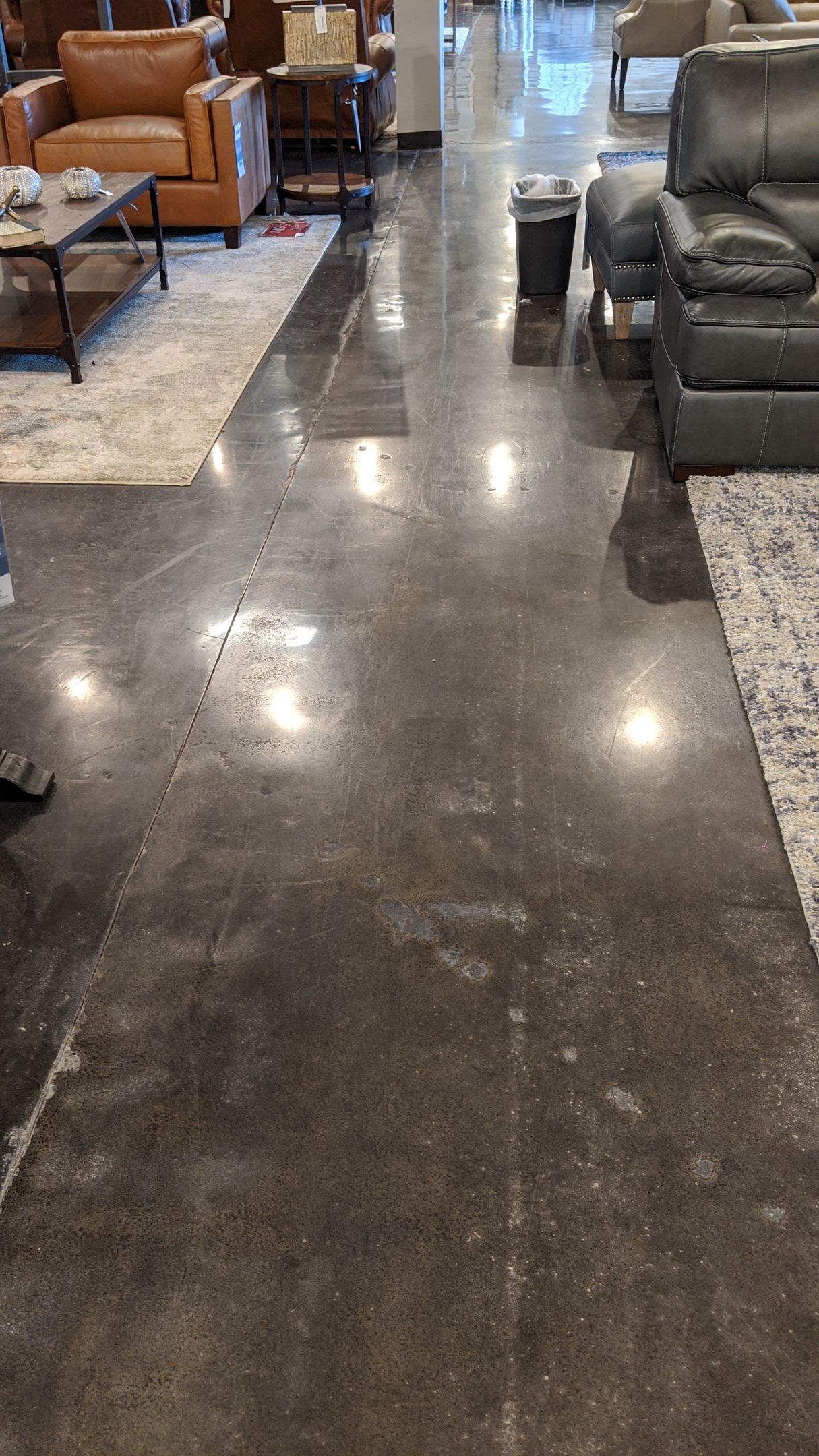 Polished concrete floor in a furniture store with reflected ceiling lights.