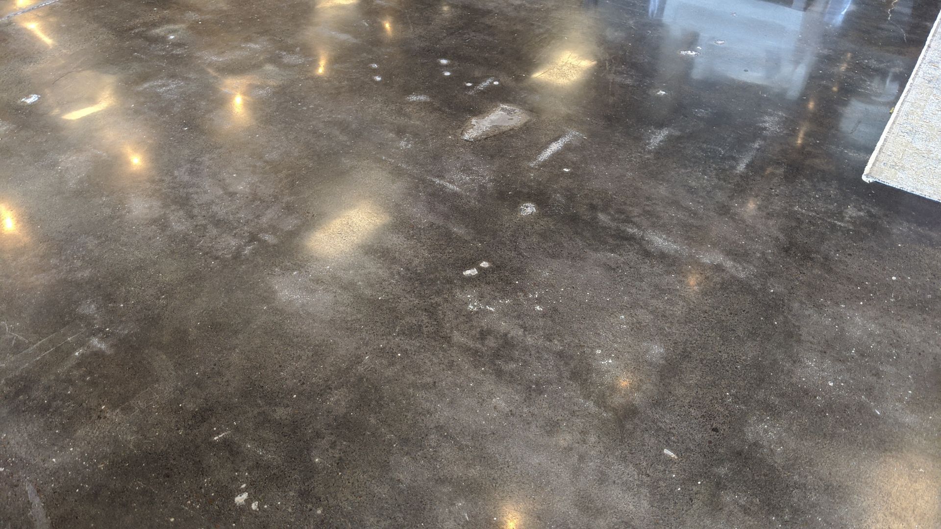 Dark, mottled floor with scattered light reflections. Patches of dust or residue are visible.