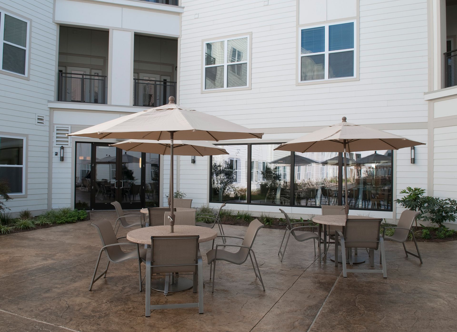 Outdoor seating area with tables, chairs, and umbrellas. Building exterior in the background.