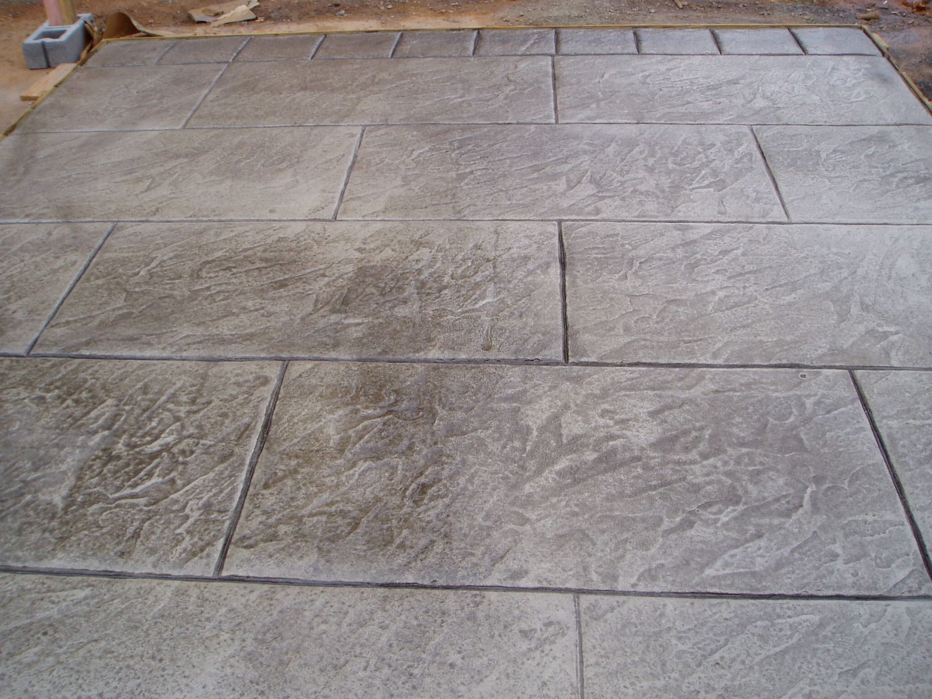 Concrete patio with rectangular stone pattern, gray color.
