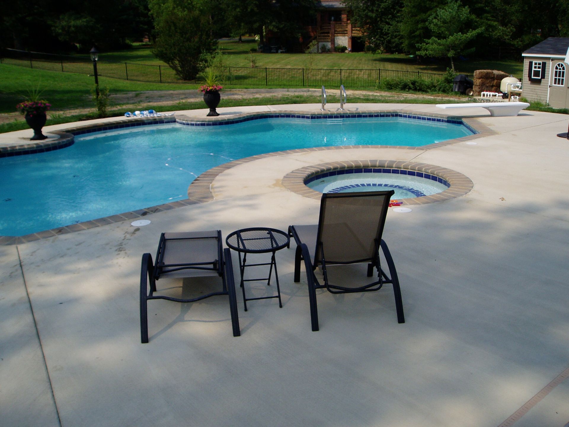 Swimming pool with lounge chairs on a concrete patio.
