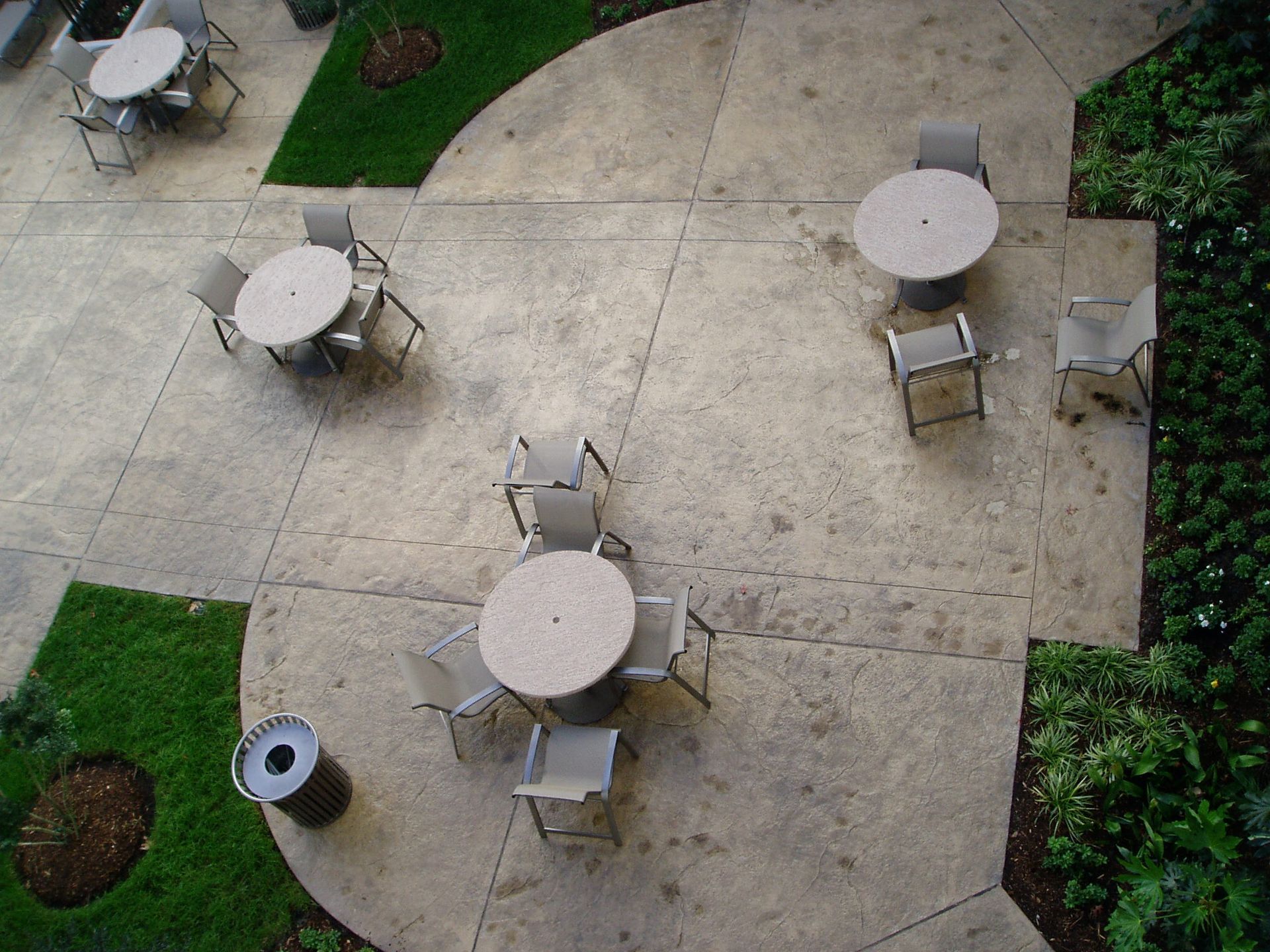 Overhead view of outdoor seating area with concrete patio, round tables, and chairs.