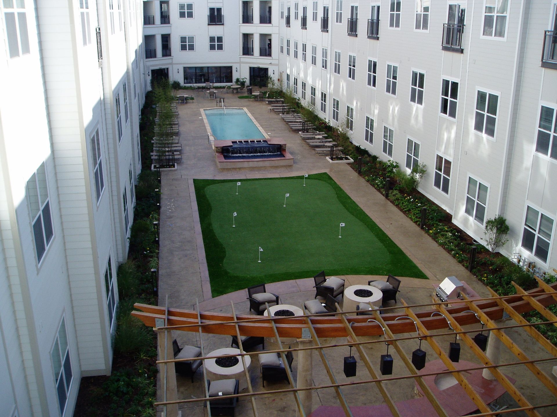 Courtyard with pool, putting green, seating, and multi-story apartment buildings.