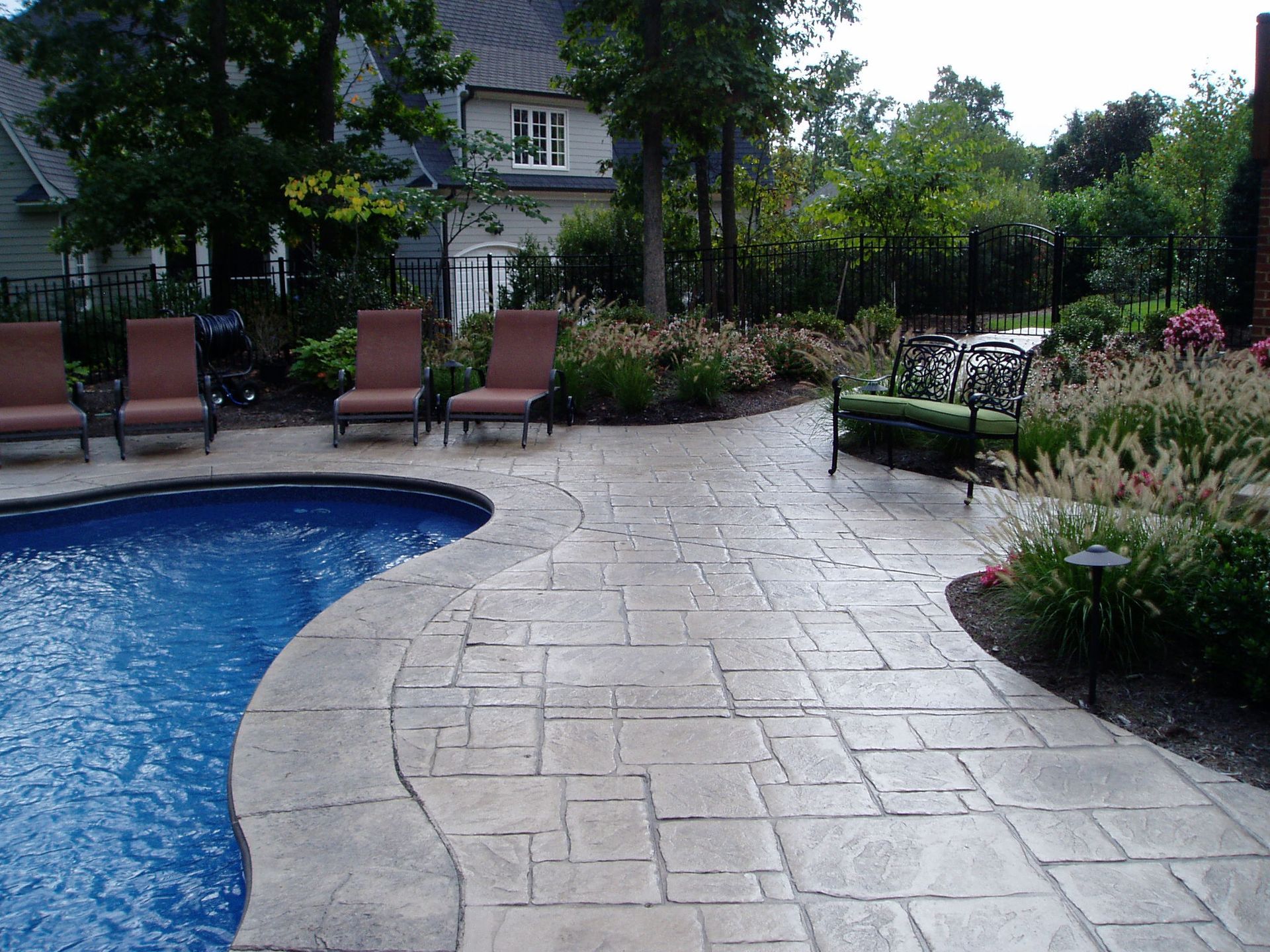 Poolside patio with lounge chairs, blue pool, and landscaping.