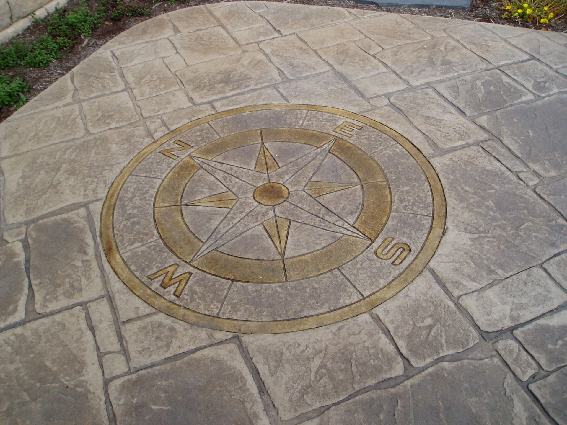 Compass design embedded in textured, stamped concrete patio.