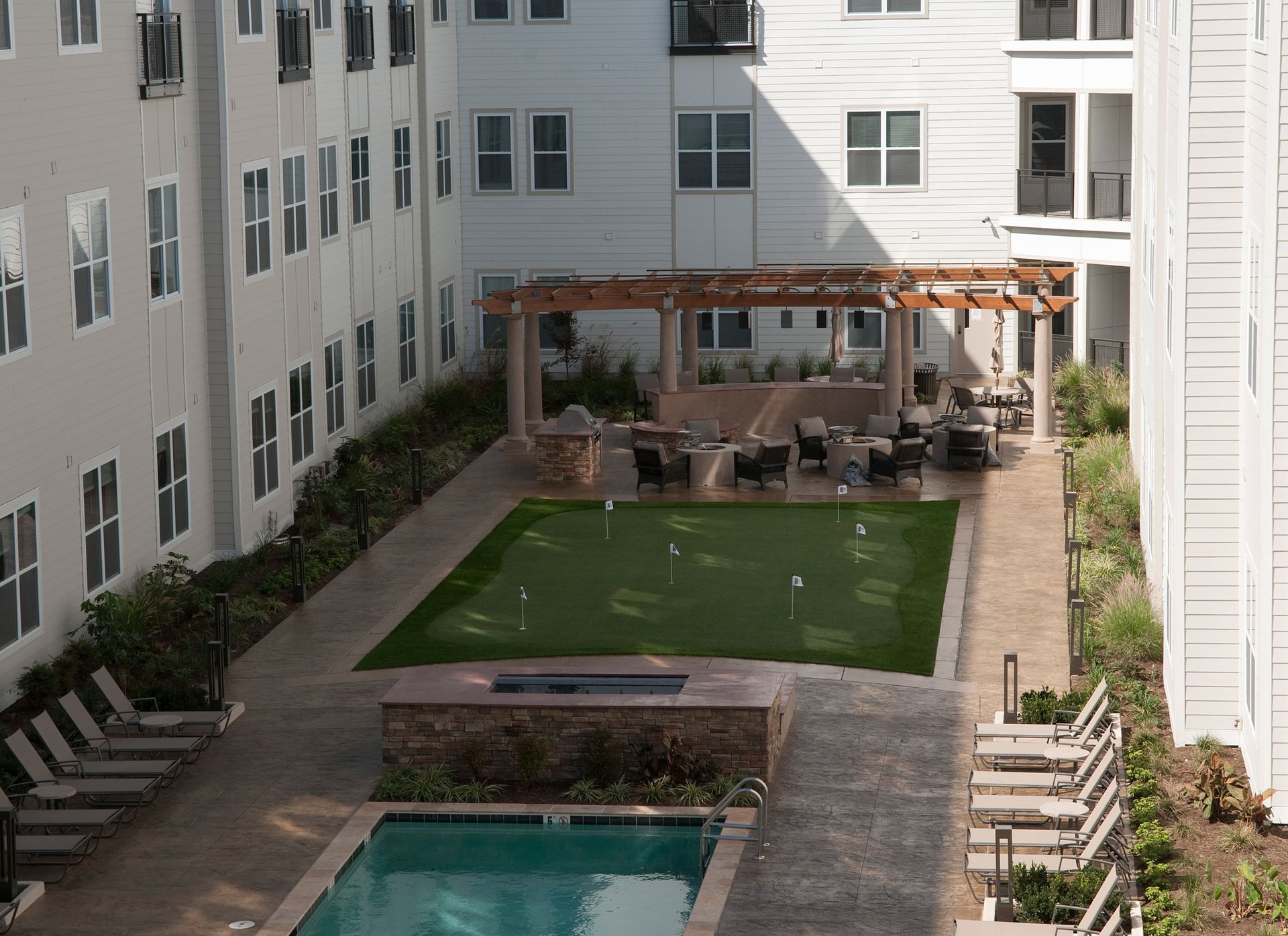 Courtyard with pool, putting green, seating, and multi-story buildings.