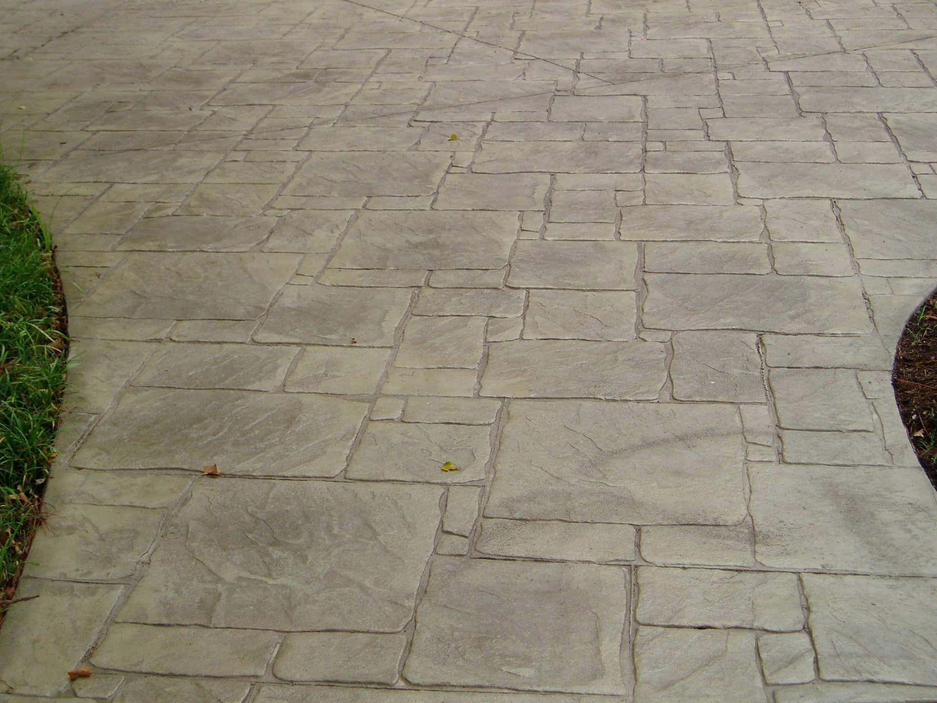 Stamped concrete driveway with a flagstone pattern. Gray.