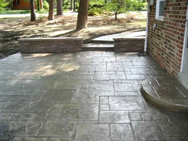 Stamped concrete patio with brick wall and steps.