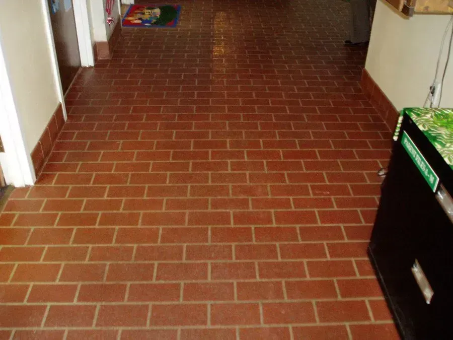 Brick-patterned terracotta tile floor in a hallway.
