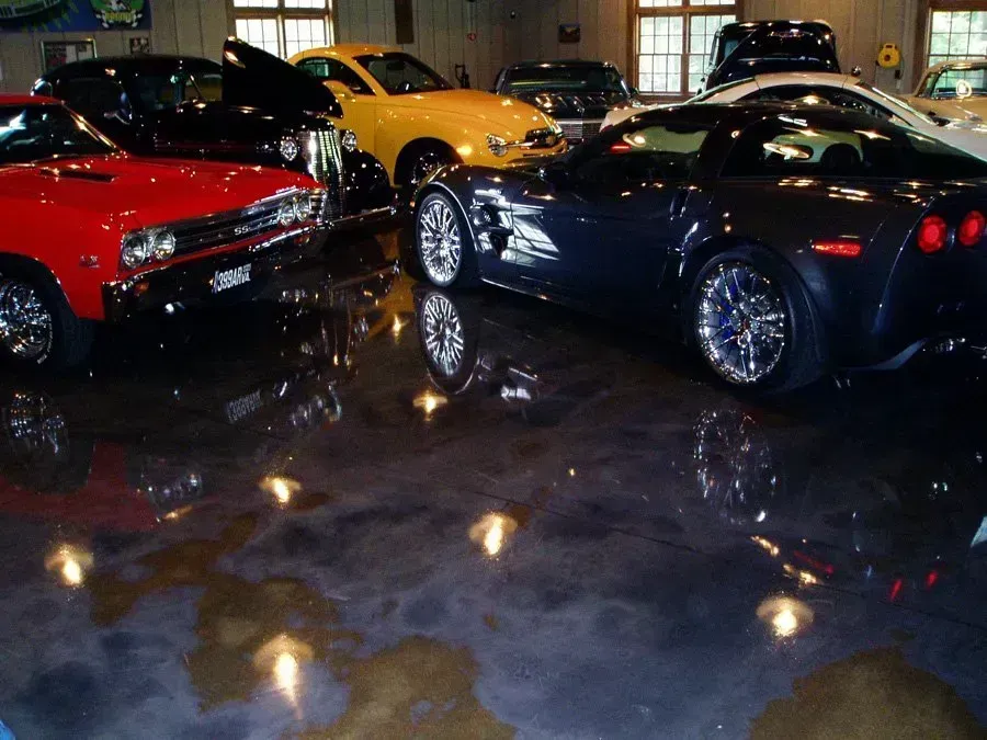 Cars parked on a shiny, reflective garage floor. Various colors, including red, yellow, and black.