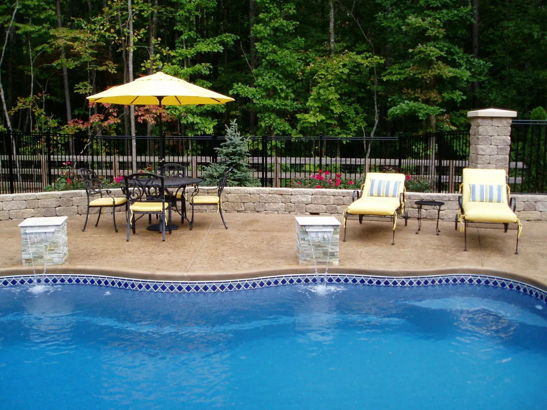 Poolside patio with yellow umbrella, furniture, lounge chairs, and blue pool.
