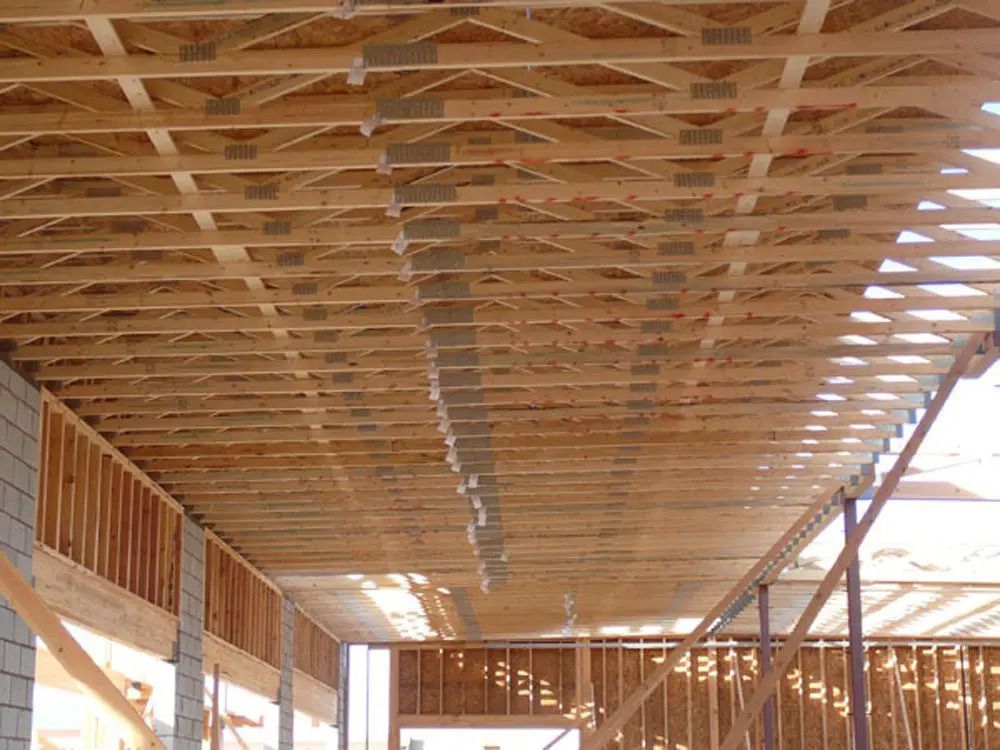 The ceiling of a building under construction is made of wooden beams.