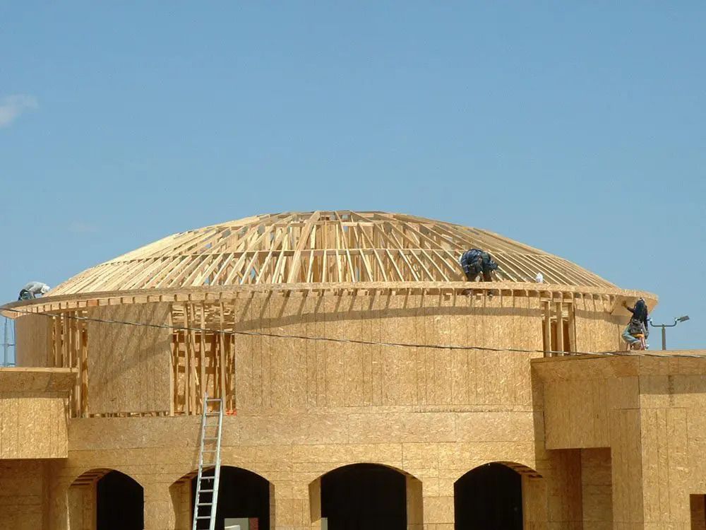 A dome shaped building under construction with a blue sky in the background