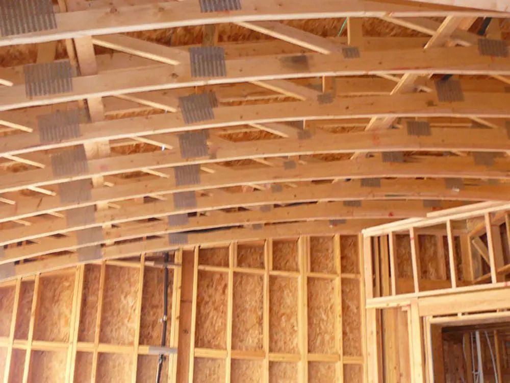 The ceiling of a building under construction is made of wooden beams.