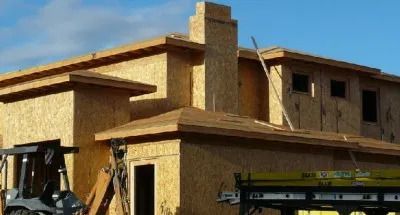 A forklift is parked in front of a house under construction.
