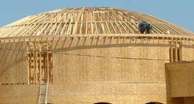 A man is working on the roof of a dome shaped building.