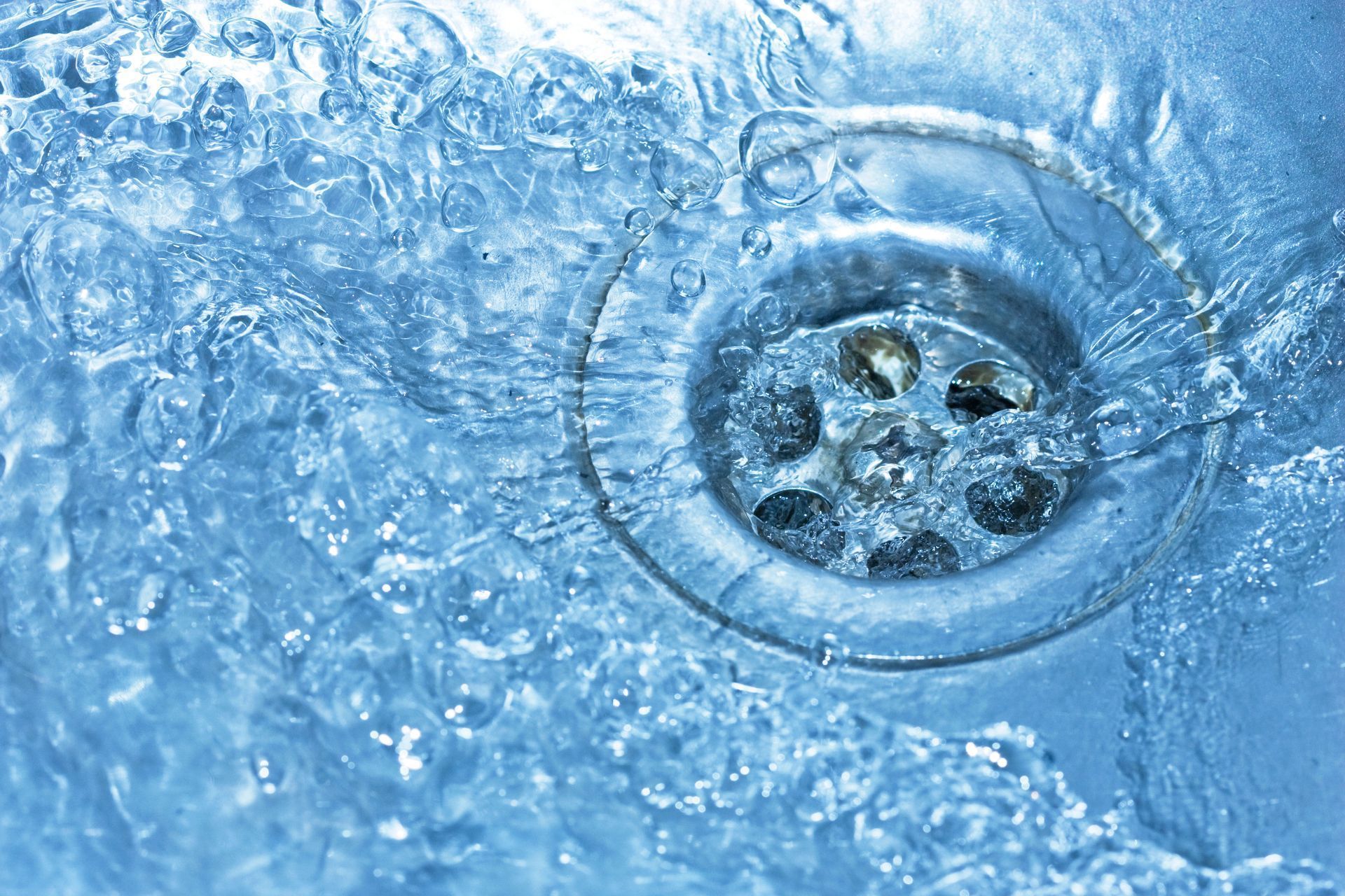Water flowing into a drain in a stainless steel sink.