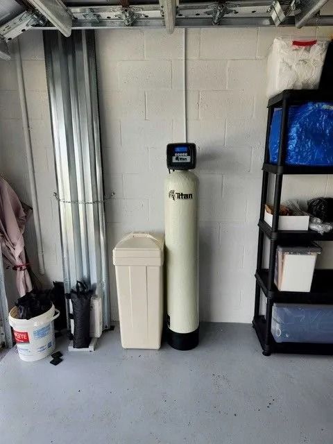 Water softener system and storage shelves in a garage.
