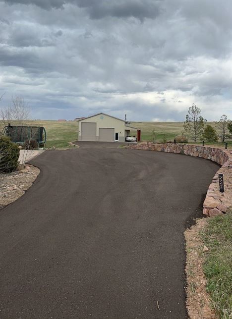 A driveway leading to a house on a cloudy day.