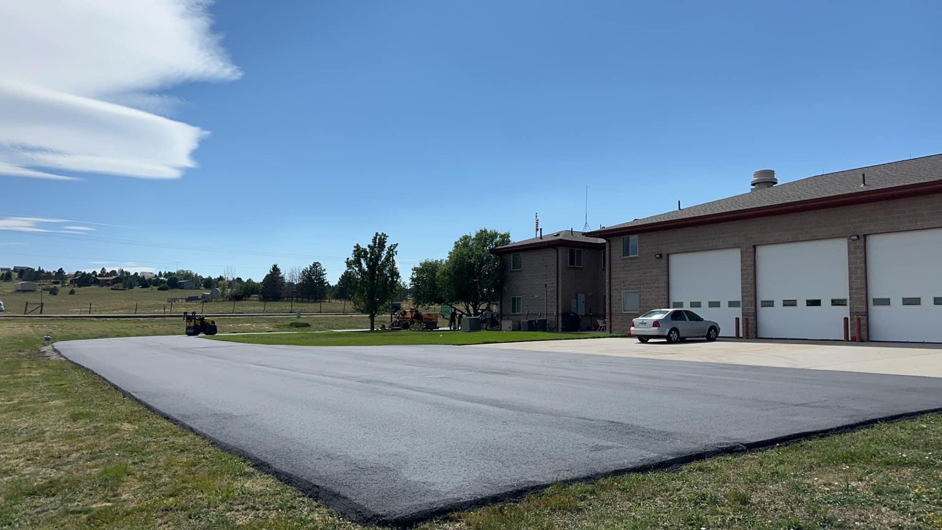 A car is parked in an asphalt driveway in front of a garage.