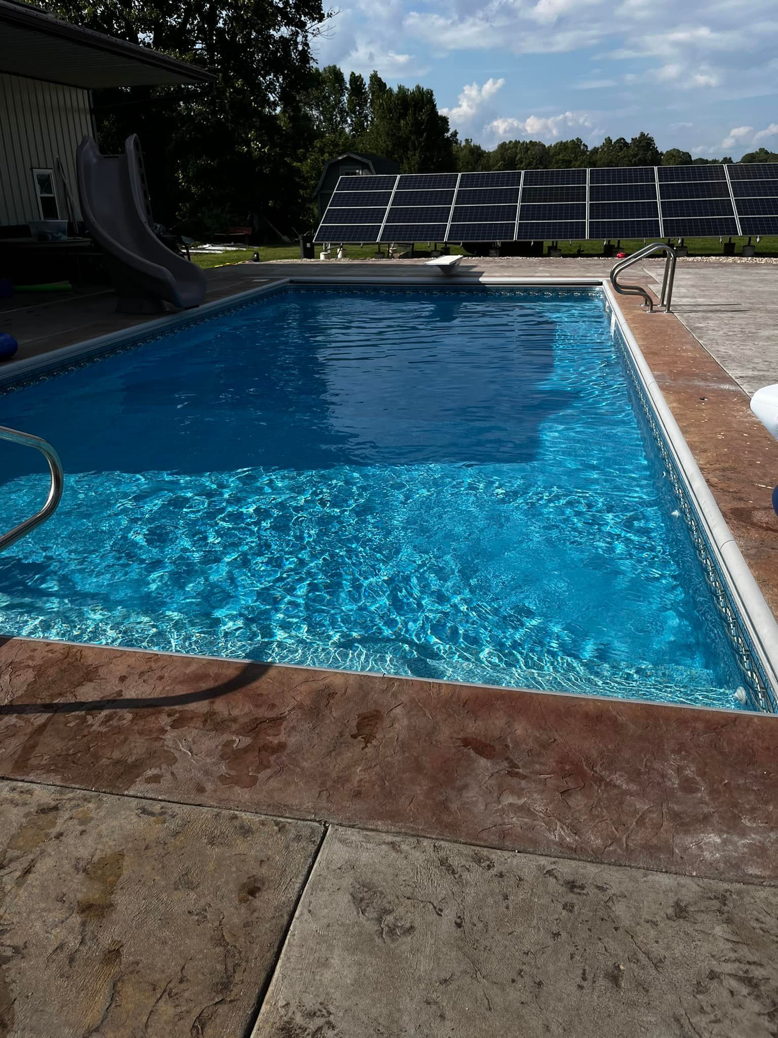 A large swimming pool with a slide and solar panels in the background