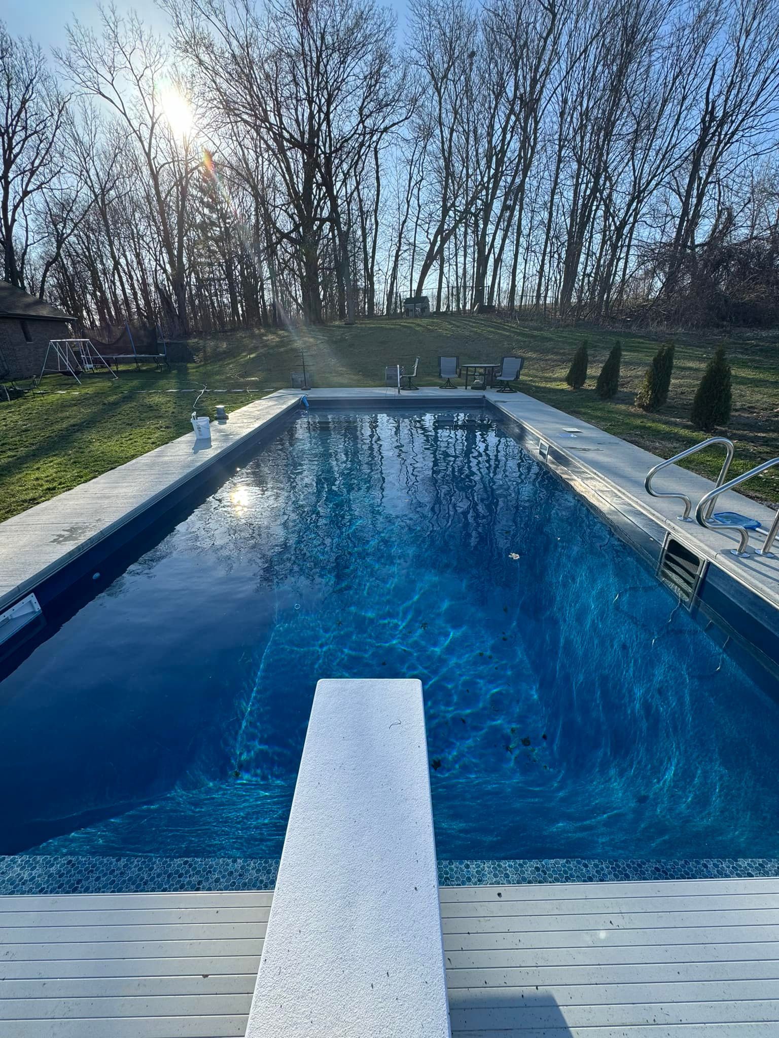 A large swimming pool with a diving board in the middle of it.