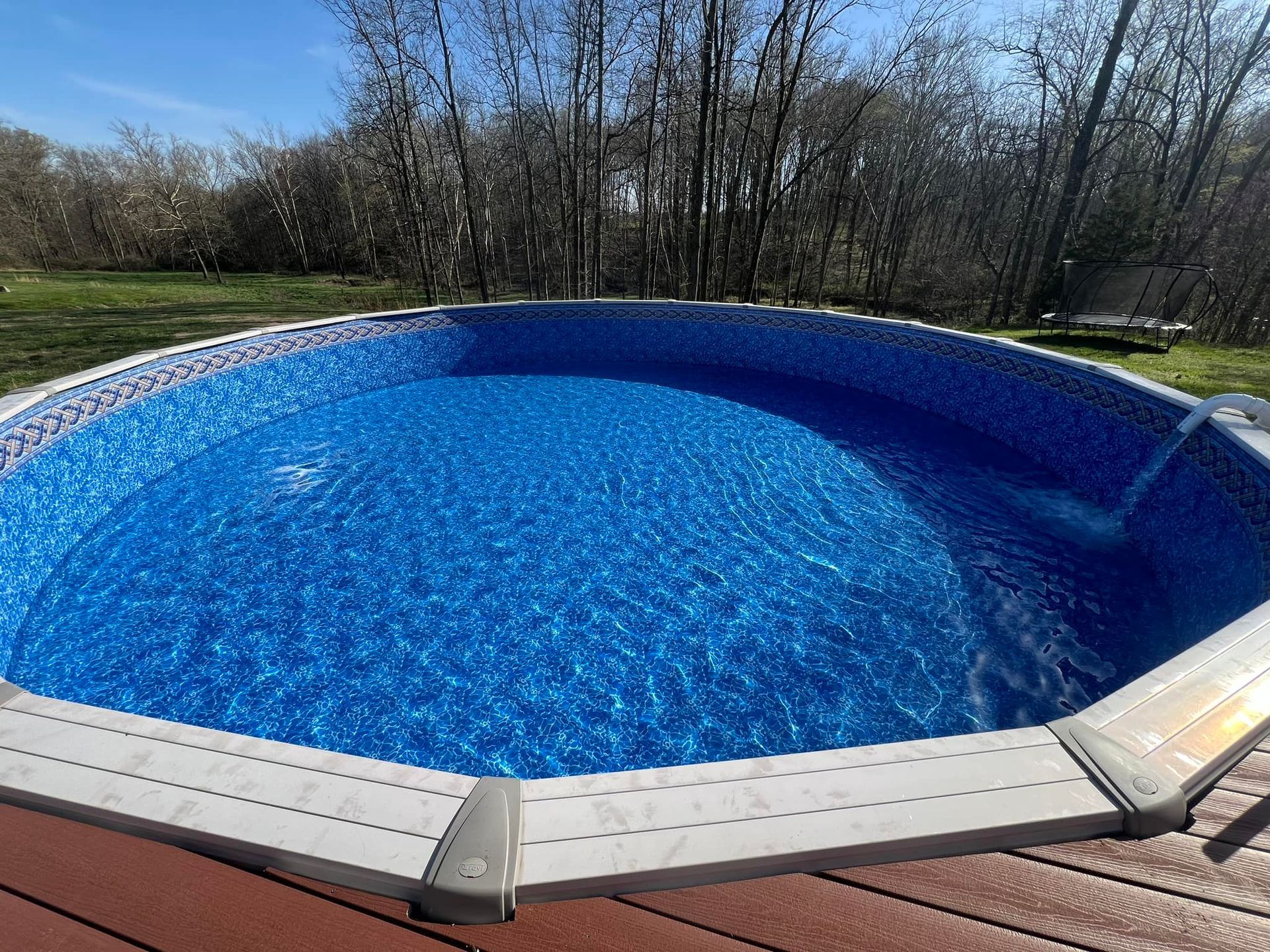 A large swimming pool is sitting on top of a wooden deck.