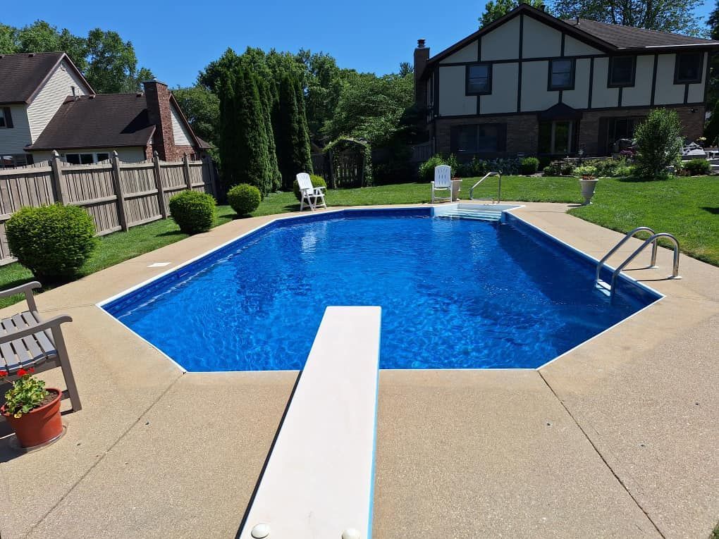 A large swimming pool with a diving board in front of a house