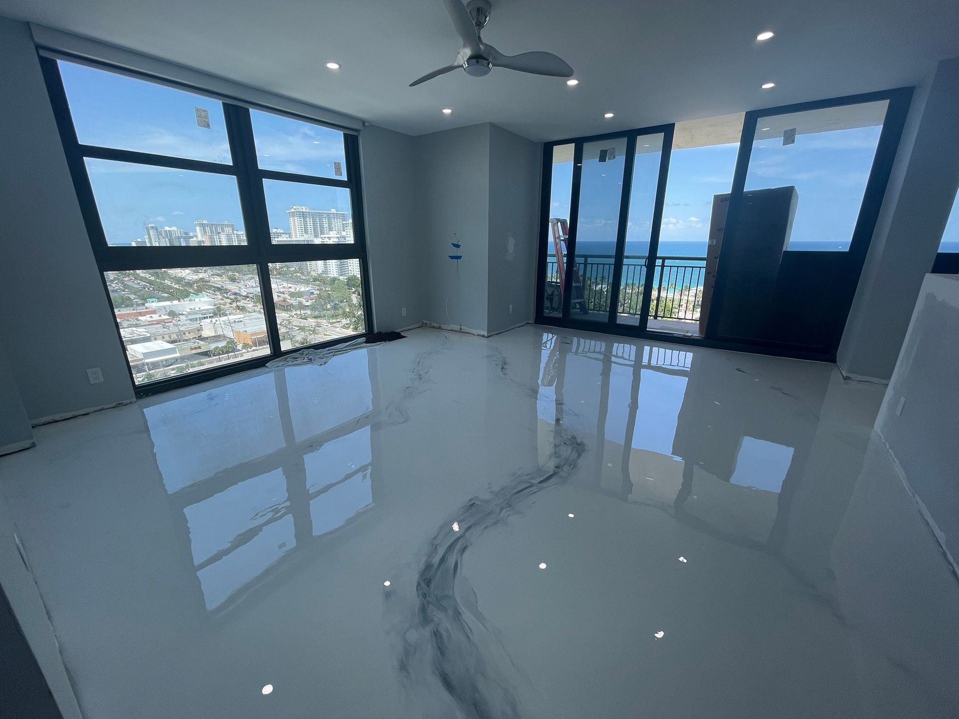 A large room with a lot of windows and a ceiling fan.