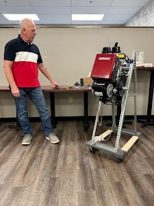 A man is standing next to a machine on a cart in a room.