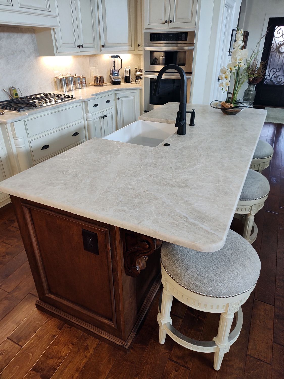 A kitchen with a large island, sink, and stools.