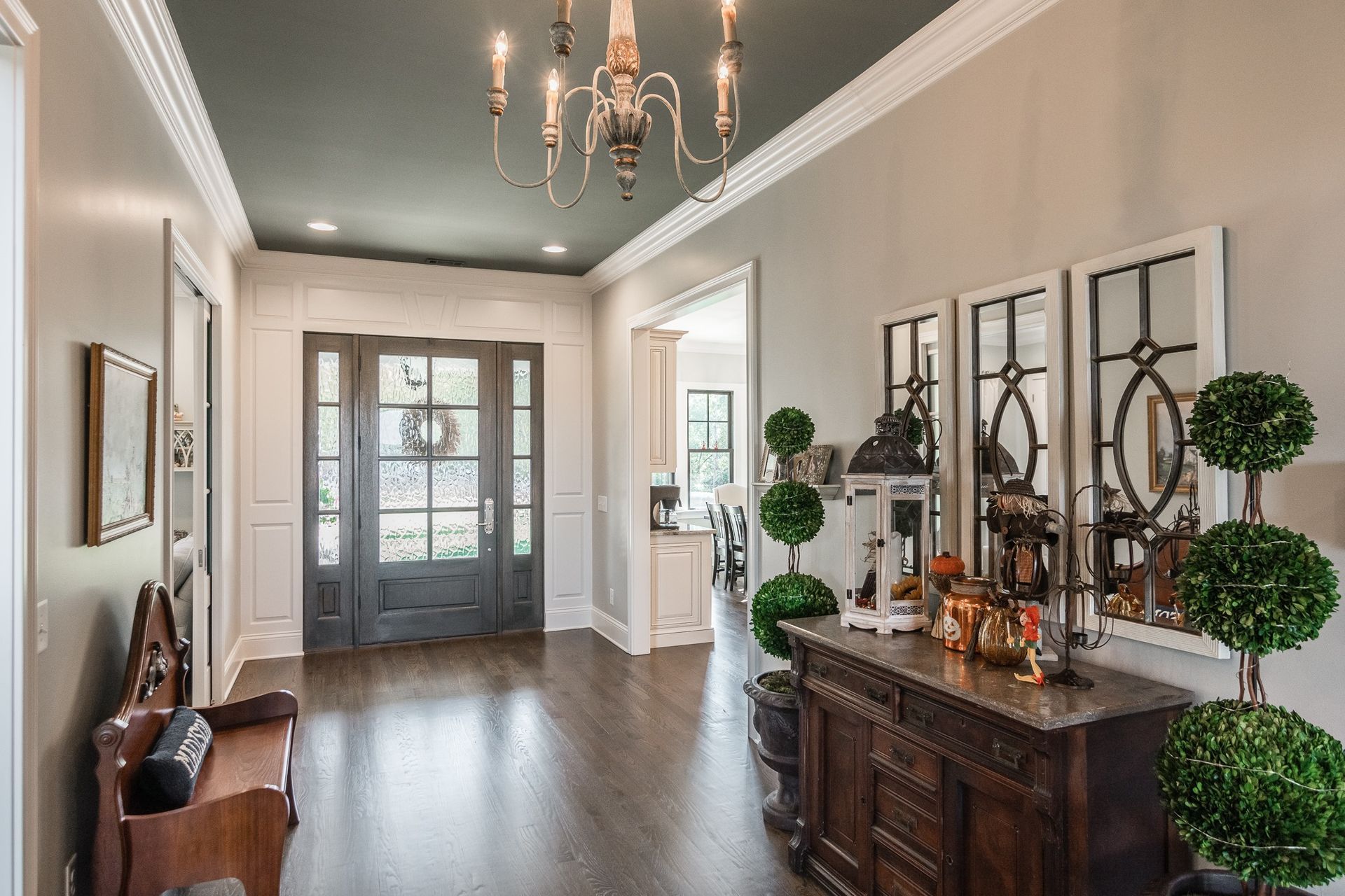 A hallway in a house with a chandelier and a dresser.
