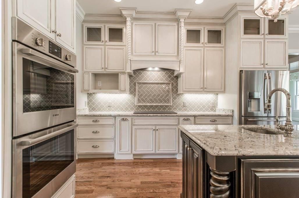 A kitchen with white cabinets , granite counter tops , stainless steel appliances and a large island.