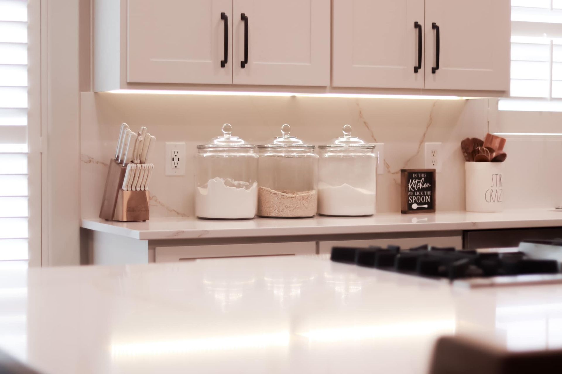 A kitchen with white cabinets and a stove top oven.