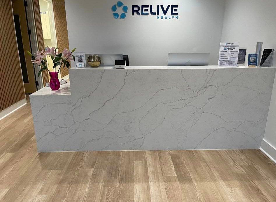 A reception desk in a medical office with a vase of flowers on it.