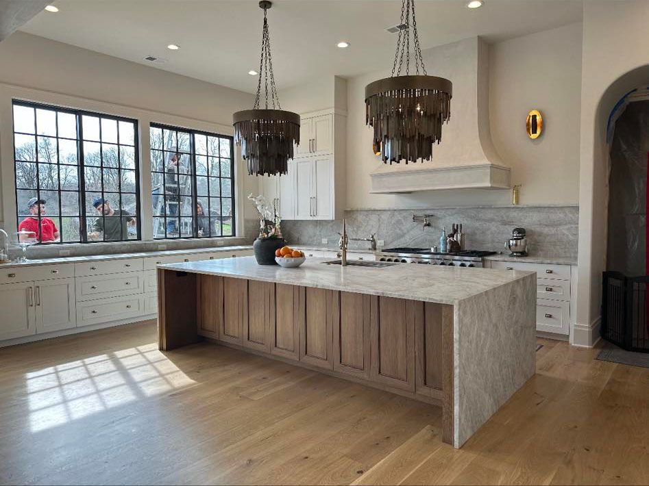 A large kitchen with a large island and two chandeliers hanging from the ceiling.