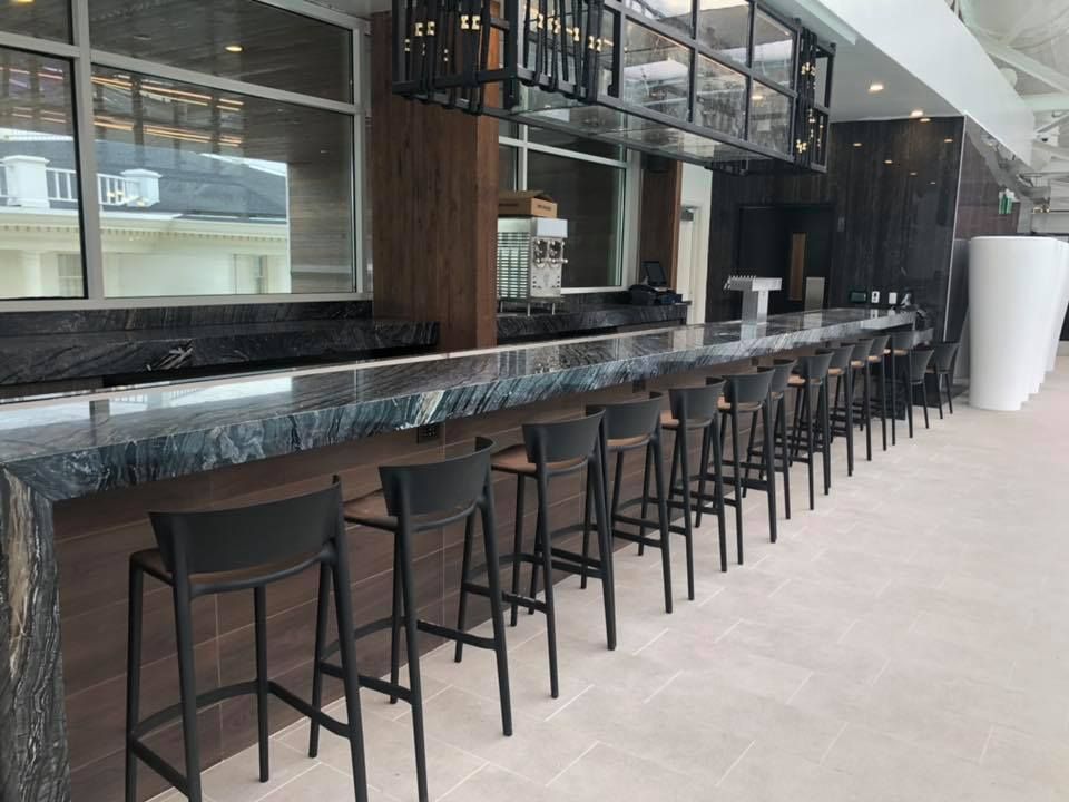A long bar with stools and a large window in a restaurant.