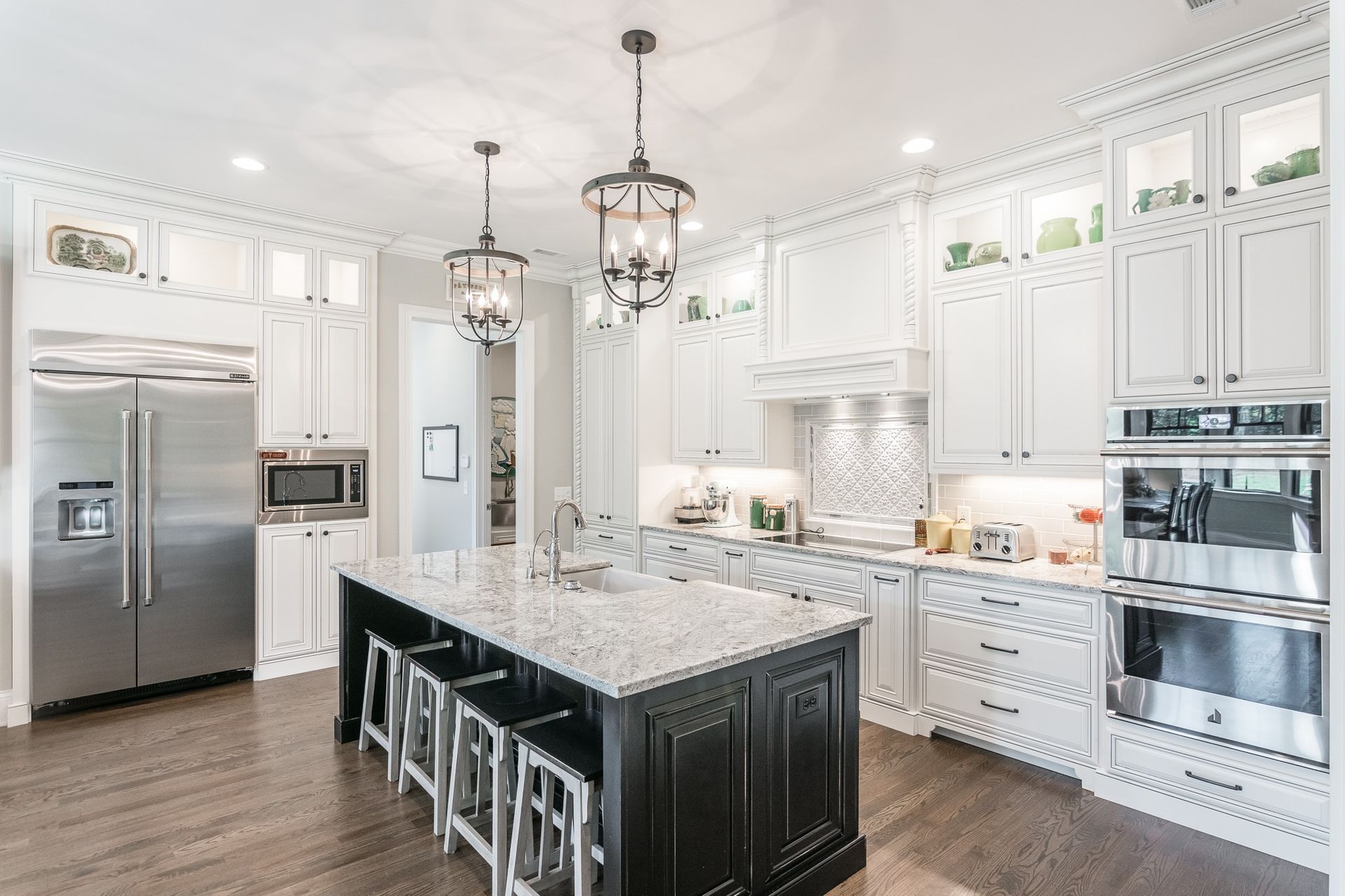A kitchen with white cabinets and stainless steel appliances and a large island.