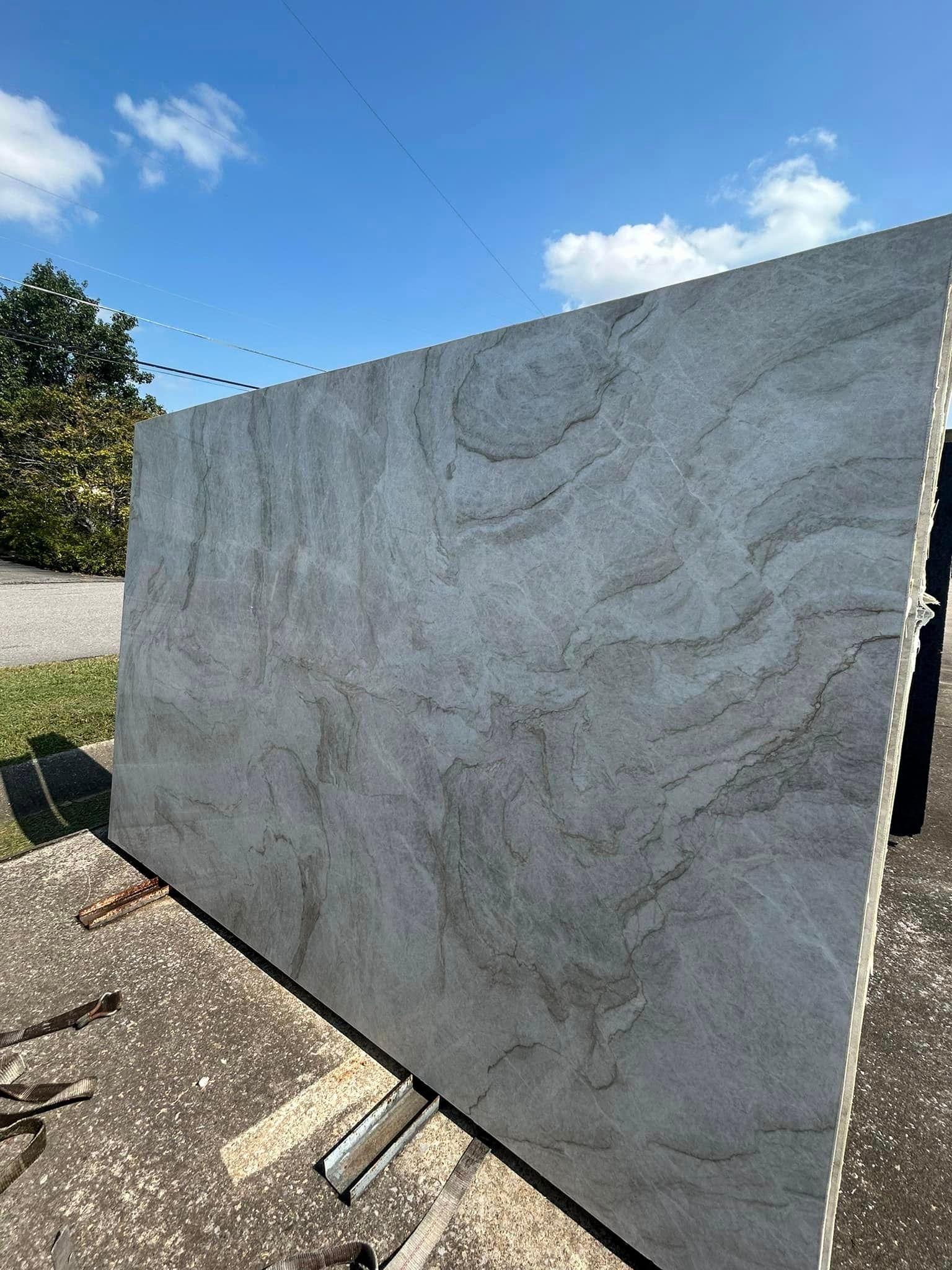 A large slab of granite is sitting on the ground in a parking lot.