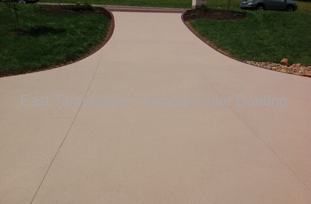 A concrete driveway with a car parked on the side of it.