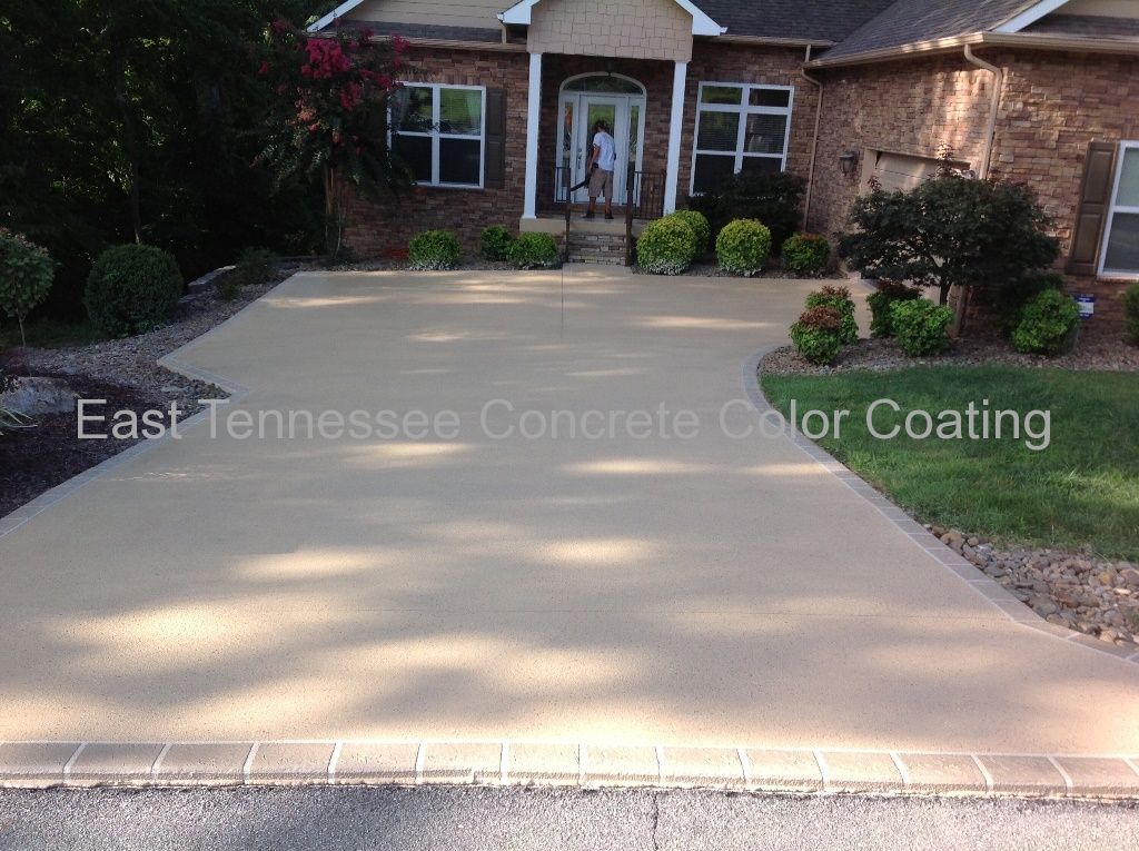 A brick house with a concrete driveway in front of it.