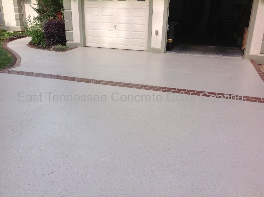 A concrete driveway with a brick border and a white garage door
