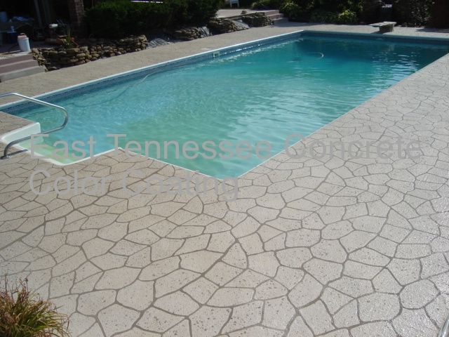 A large swimming pool with a concrete patio in front of it