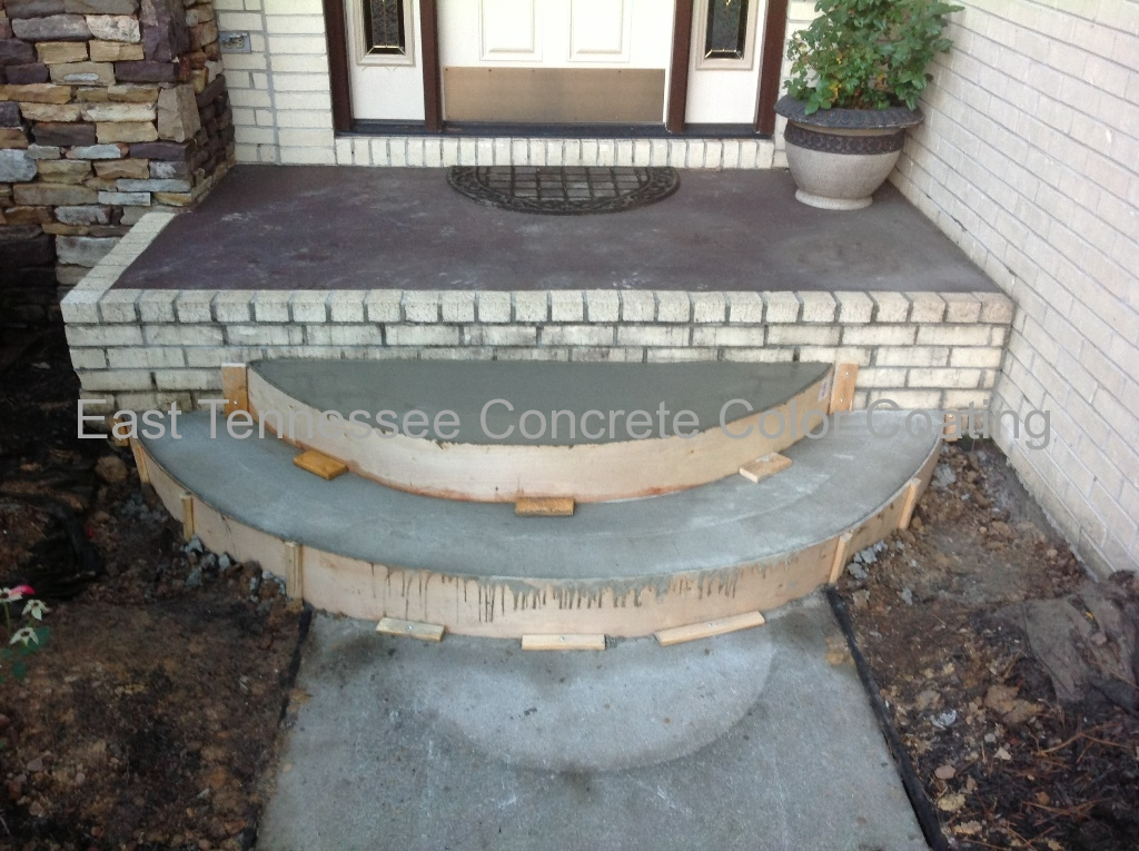A concrete walkway is being built in front of a house
