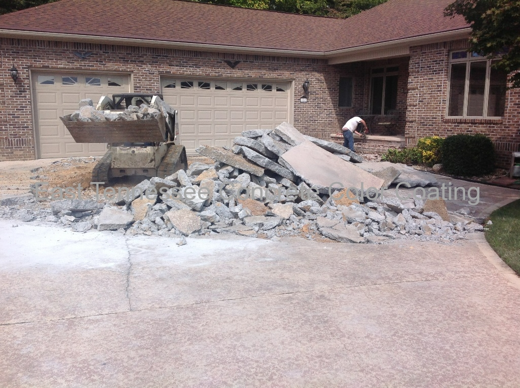 A man is working on a driveway in front of a house